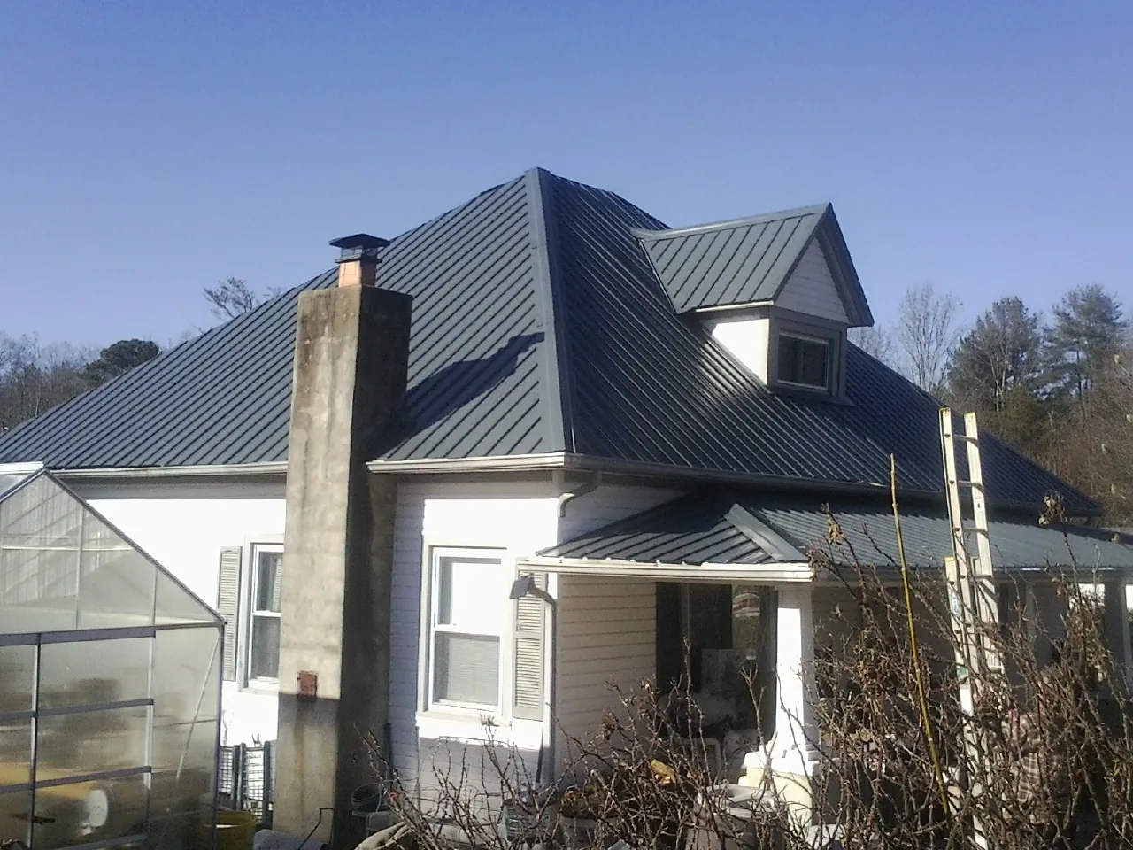 Dark blue standing seam metal roof on a white farmhouse with dormer — Slate & Tile Roof Repair by Roofing Brothers in Hornsby