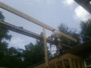 Carpenter setting a ridge beam over a new addition frame — Ice Dam Removal by Roofing Brothers in Hornsby