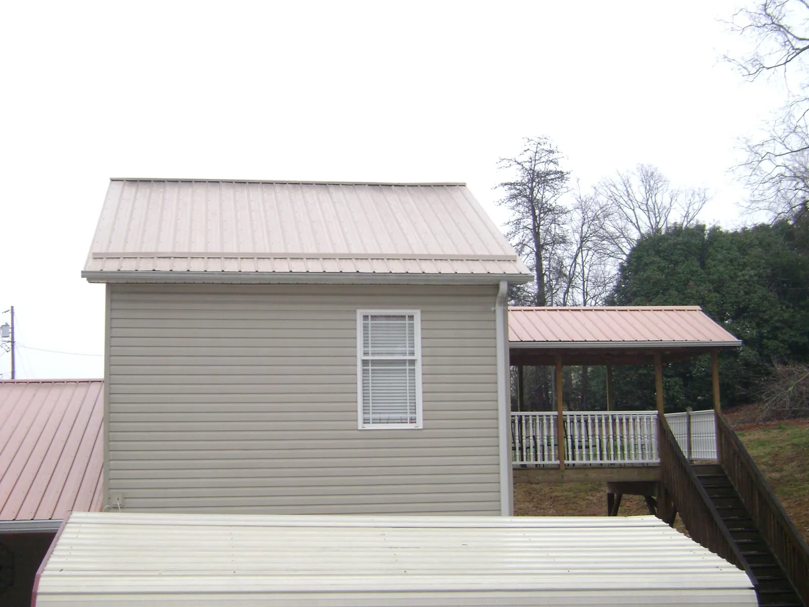 Tan metal roofs on a two story addition and attached porch, from a Roof Replacement job in Hornsby