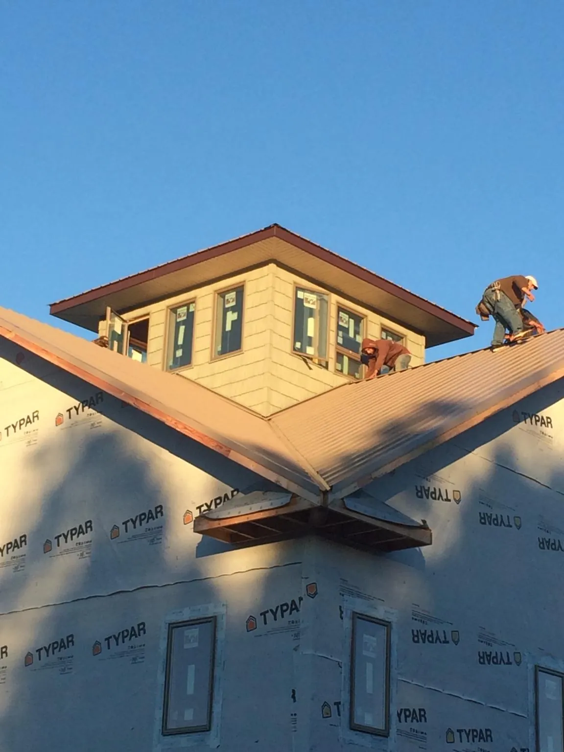 Roofers working around a rooftop cupola on a new metal roof at sunset — Roof Waterproofing in Hornsby by Roofing Brothers